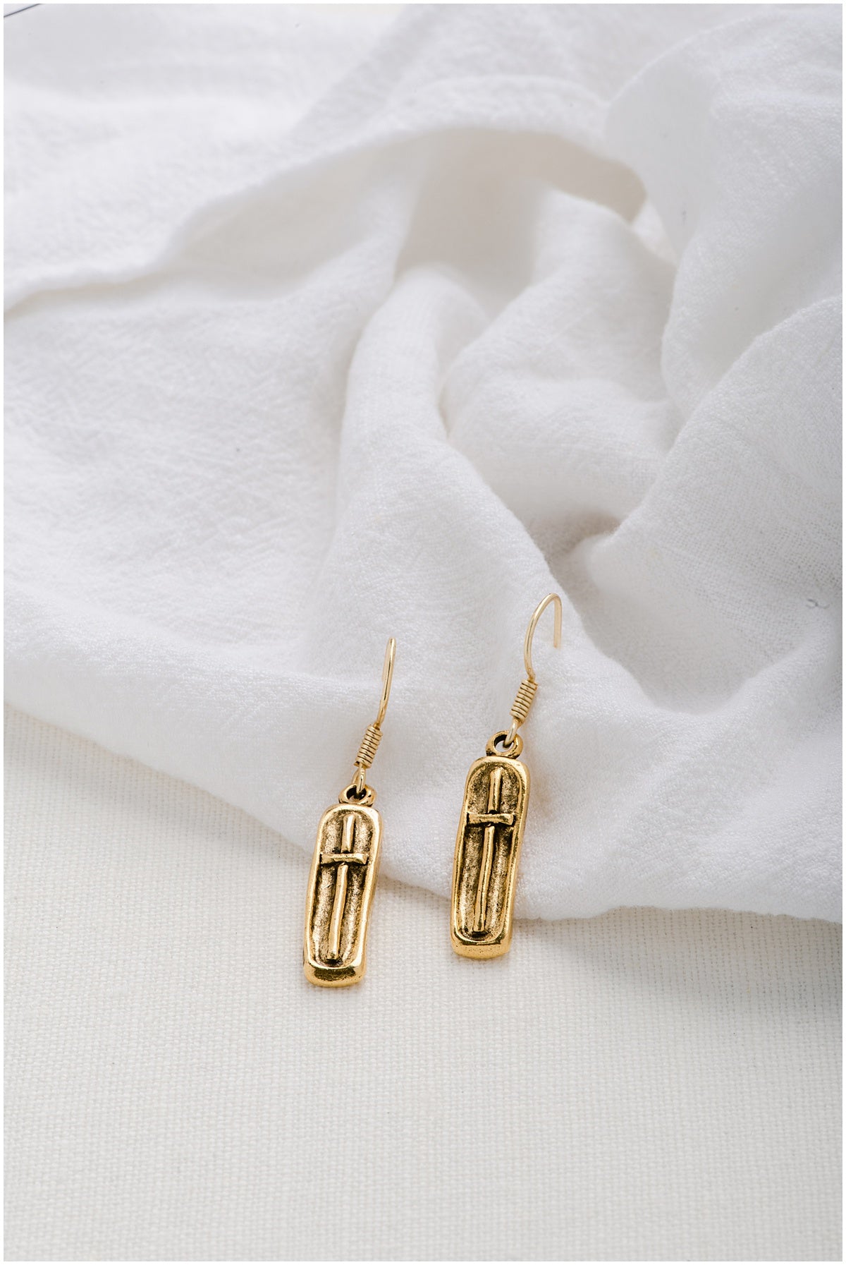 A pair of gold, rectangular earrings with a cross on top.