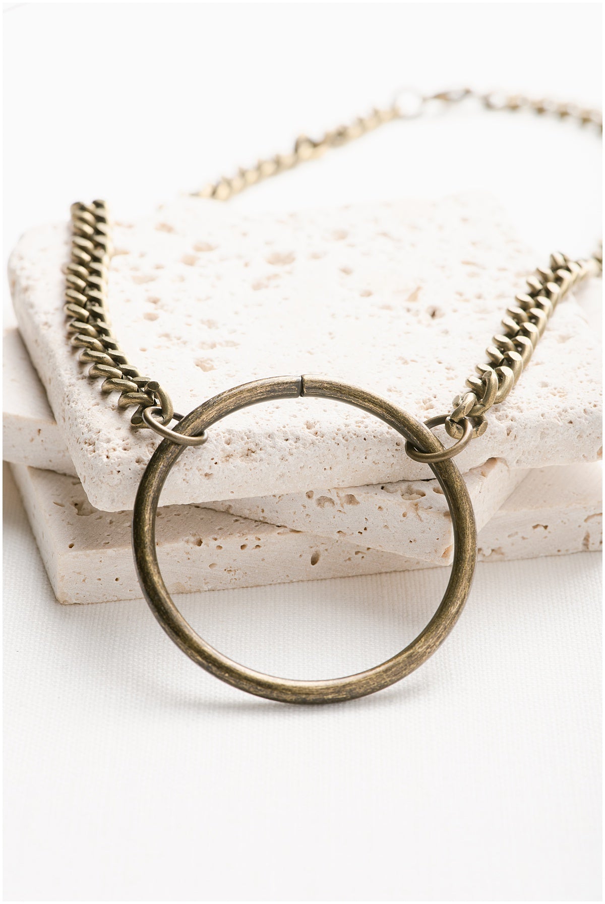 A brass necklace chain with a large round pendant.