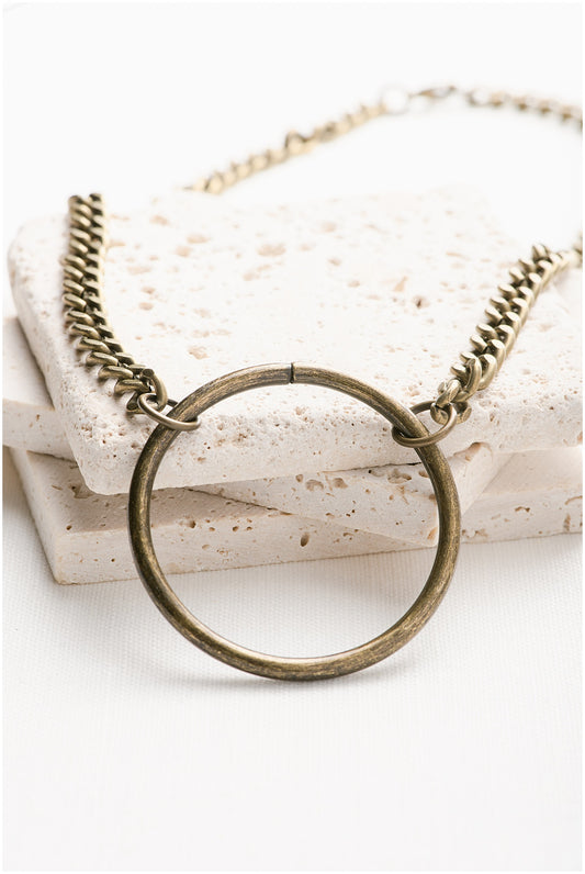 A brass necklace chain with a large round pendant.