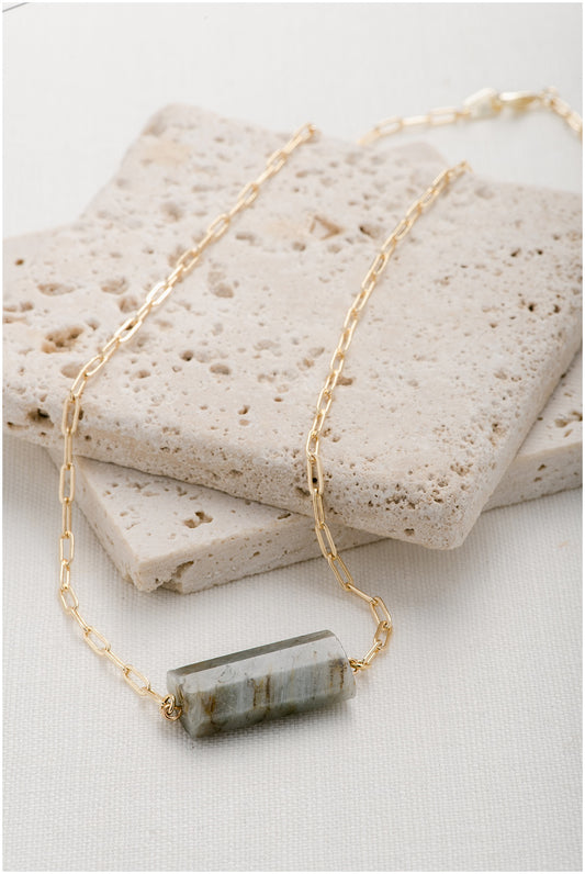 Gold, paperclip chain with a blue/brown octagonal gemstone pendant.