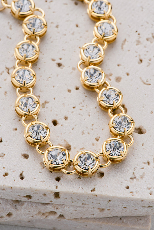 A gold necklace with two different-sized crystals alternating sizes throughout the necklace.