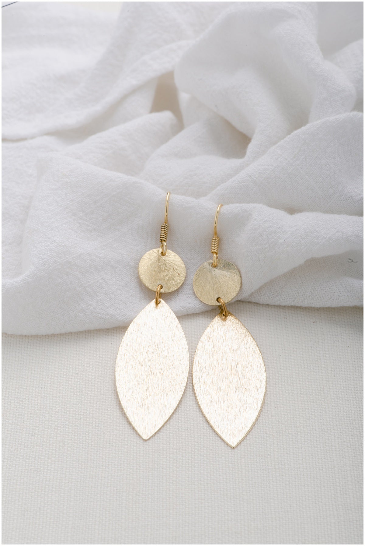 A small gold circle with a gold, petal-shape pendant hanging from it.