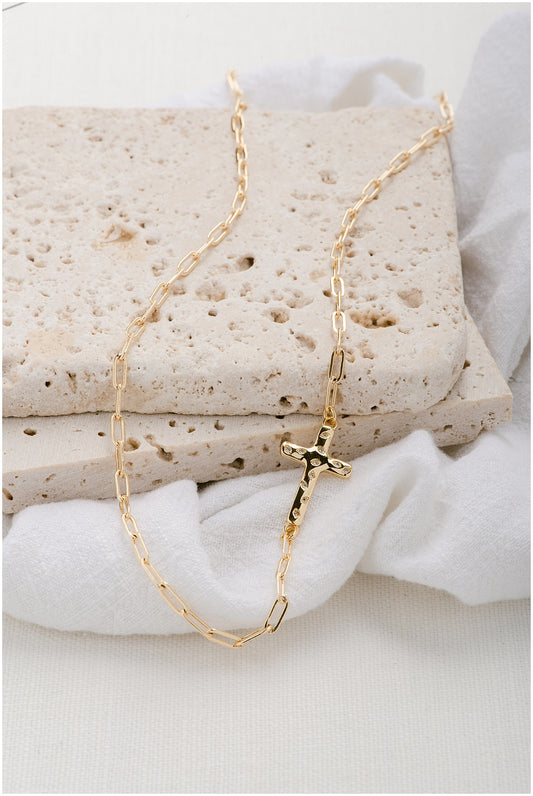 A gold paperclip chain with a gold cross pendant with elegant crystal accents.