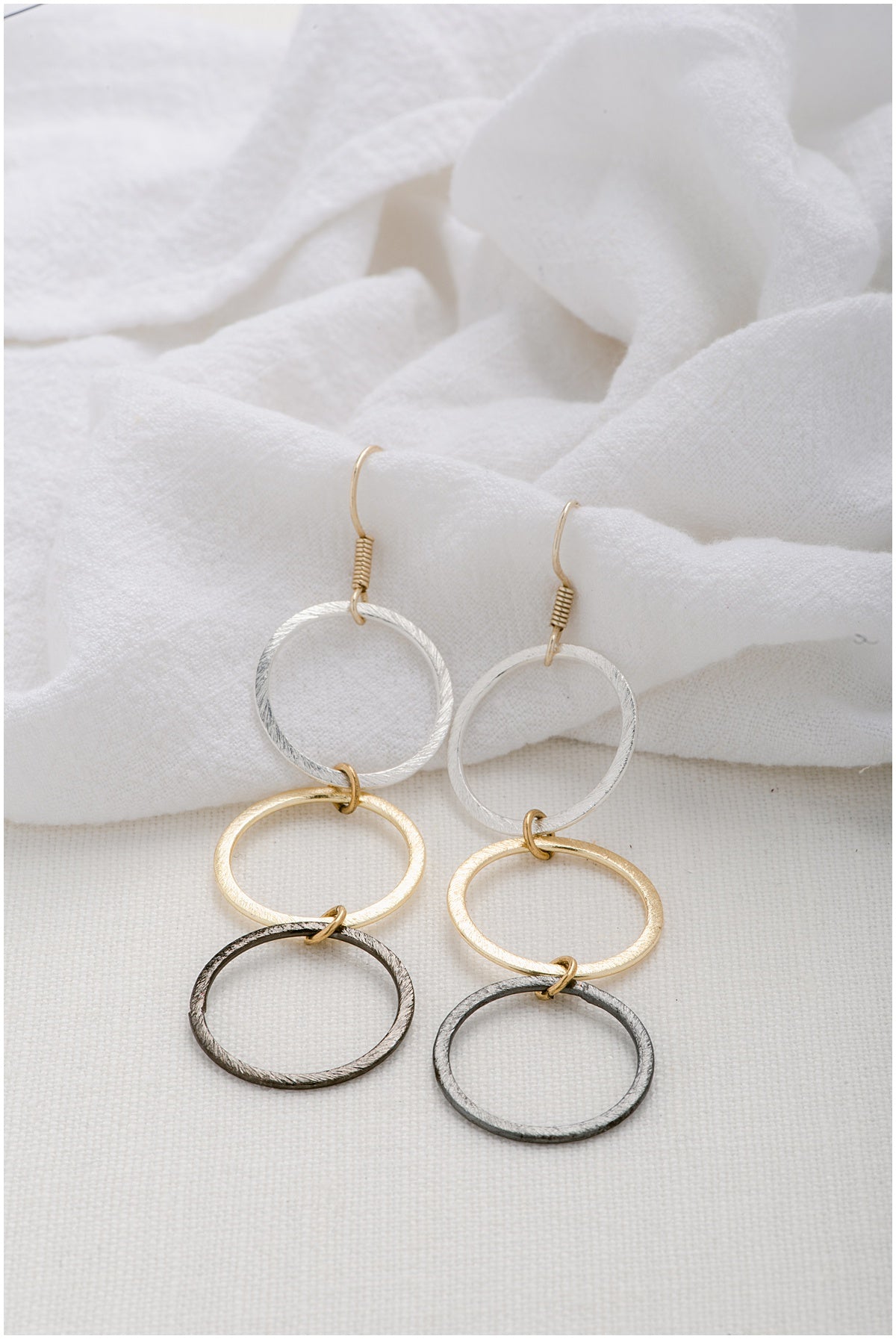Tri-color earrings with a silver circle, a gold circle, and a gunmetal circle. This picture features our classic size earring.