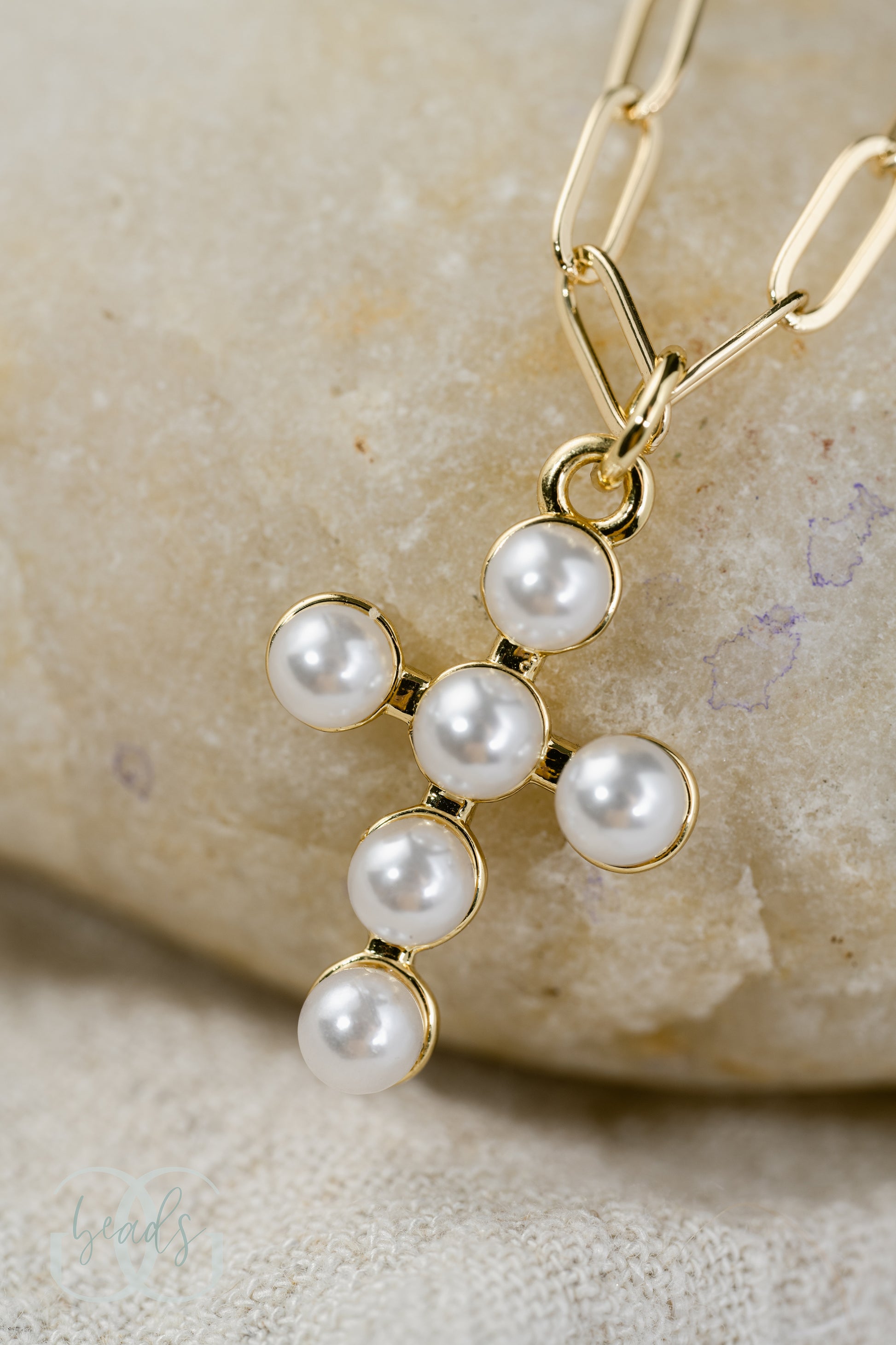 A 1" pearl cross pendant on a gold chain.